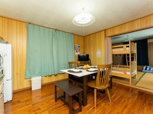 a dining room with a table and chairs and a bunk bed at Nabee no Yado B057 in Onna