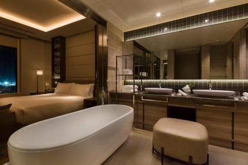 a bathroom with a tub and two sinks and a bed at Hilton Hiroshima in Hiroshima
