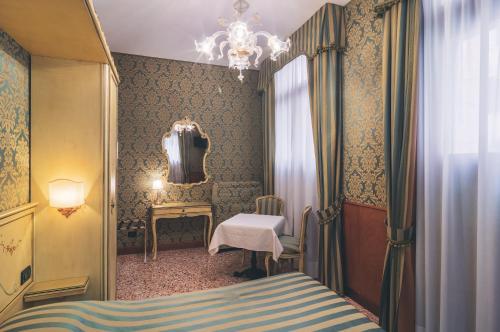 a bedroom with a bed and a chair and a mirror at Hotel Al Malcanton in Venice