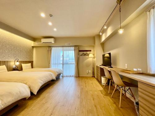 una camera d'albergo con 2 letti e una scrivania di ホテル天使館 久茂地 -Tenshi-Kan- a Naha