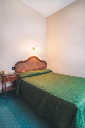 a bedroom with a green bed and a night stand at Hotel Al Malcanton in Venice