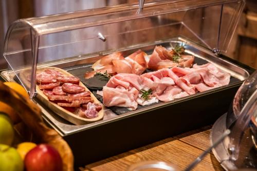 a display case with ham and other meats and fruit at Brieis Relais Alpino in Marmora