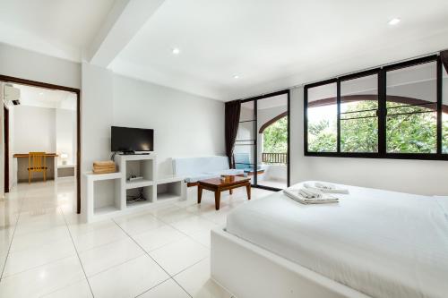 a white bedroom with a bed and a living room at Prinz Garden Villa in Hua Hin