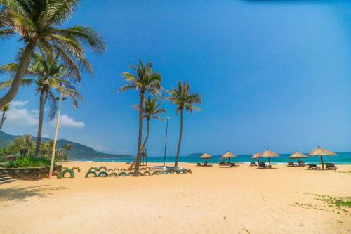 a beach with umbrellas and palm trees and the ocean at Narada Resort & Spa Perfume Bay Sanya - All Villas in Lingshui