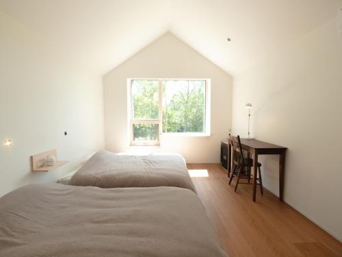 - une chambre avec un lit, un bureau et une fenêtre dans l'établissement Coboushi オモヤ, à Niseko