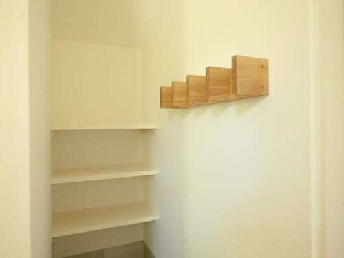 a closet with white shelves and a wooden shelf at Coboushi オモヤ in Niseko
