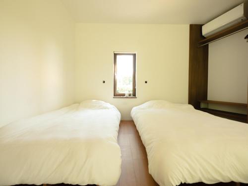 two white beds in a room with a window at Coboushi ハナレ in Niseko