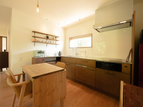 a kitchen with wooden cabinets and a wooden table at Coboushi ハナレ in Niseko