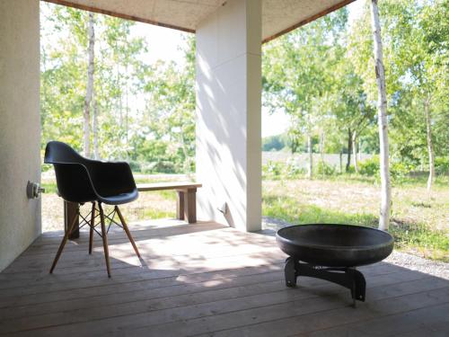 a black chair and a table on a porch at Coboushi ハナレ in Niseko