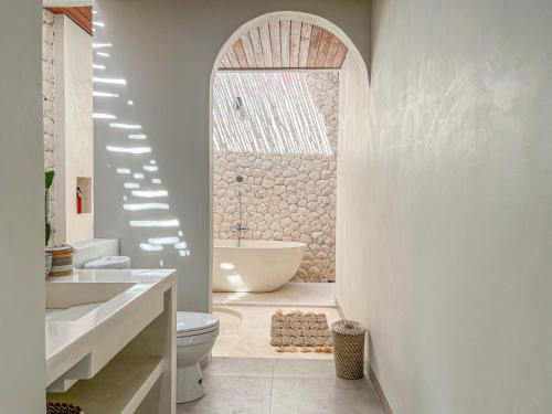 uma casa de banho com uma banheira, um lavatório e um WC. em Moana Villa & Suites Bingin em Uluwatu