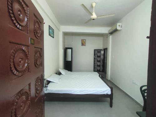 1 dormitorio con 1 cama y ventilador de techo en Jinnens Tourist Home, en Ponnāni