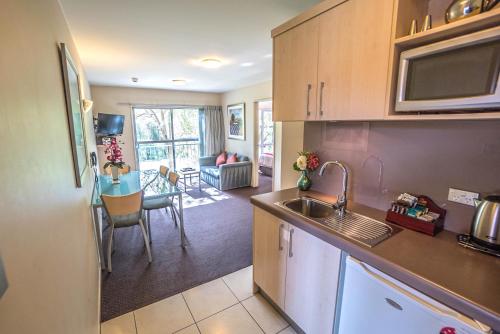 a kitchen with a sink and a living room at Kings Of Riccarton Motel in Christchurch