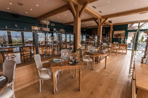 um restaurante com mesas e cadeiras de madeira e janelas em Le Manoir des Impressionnistes - Bord de Mer em Honfleur