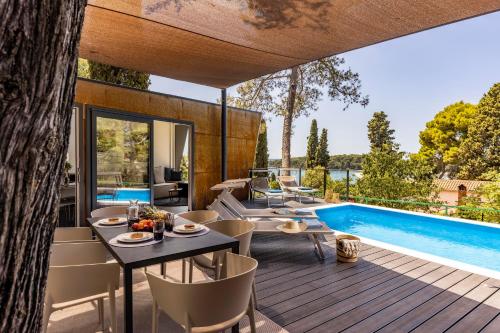 een terras met een tafel en stoelen en een zwembad bij Porton Nature Hideouts in Rovinj