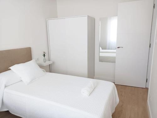 a white bedroom with a white bed and a mirror at AREAS NEGRAS- Apartamento centro de Cedeira. in Cedeira