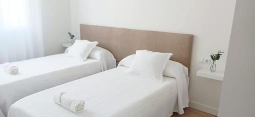 two beds in a room with white sheets and white pillows at AREAS NEGRAS- Apartamento centro de Cedeira. in Cedeira