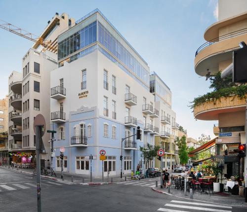 een hoog wit gebouw in een stadsstraat met een zebrapad bij Alberto by Isrotel Design in Tel Aviv