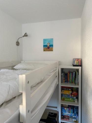 a bedroom with a white bed and a book shelf at Ferienwohnung Gustav - Moderne Maisonette-Wohnung mit Terrasse in Wangerooge