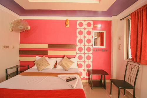 a bedroom with a bed and a red wall at Just Guest House, Chennai Airport in Chennai