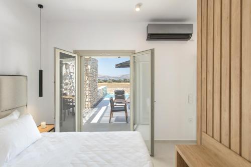 1 Schlafzimmer mit einem Bett und einem Balkon mit einem Tisch in der Unterkunft T7 LUXURY VILLAS PAROS in Kampos Paros