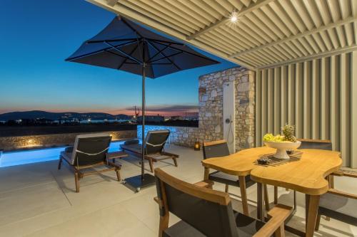 une terrasse avec une table, des chaises et un parasol dans l'établissement T7 LUXURY VILLAS PAROS, à Kampos Paros