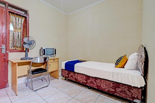 een slaapkamer met een bed, een bureau en een televisie bij SPOT ON 91482 Sentosa Home in Bandung