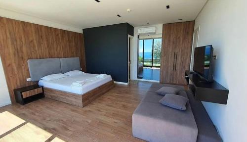 a bedroom with a bed and a couch and a television at Le Rêve Boutique Hotel in Dhërmi