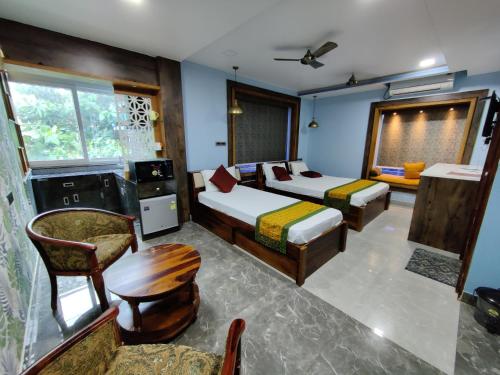 een slaapkamer met 2 bedden, een stoel en een tafel bij Sakuntala Residency in Bhubaneshwar
