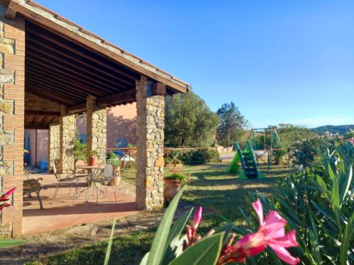 a stone house with a playground in a garden at Agriturismo La Casina in Saturnia