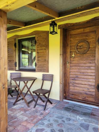a porch with two chairs and a table and a door at Domki Białogarda in Wicko