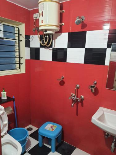 a red bathroom with a toilet and a sink at JP Deluxe in Bengaluru
