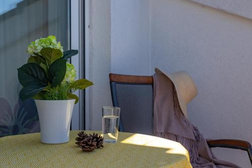 a table with a vase with a plant and a glass at TERRA MAGICA DELUXE Apartment Or Room with Private Parking, Terrace and Sea View in Rijeka