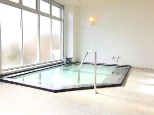 a swimming pool in a room with a large window at ISOLA Izukogen in Ito