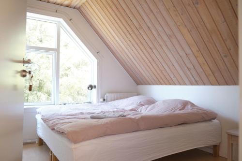 1 dormitorio con 1 cama con techo de madera en Noah's Ark, en Klitmøller