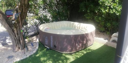 a hot tub sitting on the grass next to a tree at Mansarda con vista lago in Sulzano
