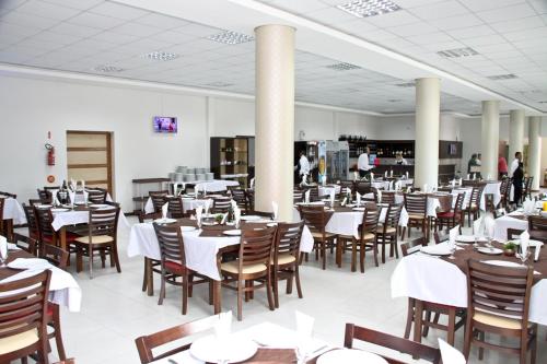 a dining room with white tables and chairs at Miotto Executive Hotel in Navegantes