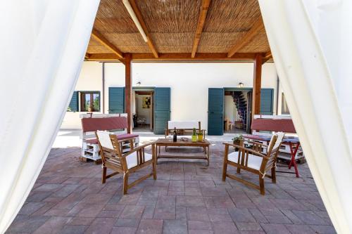 a patio with chairs and tables and a wooden ceiling at La Casa di Valverde in Alghero