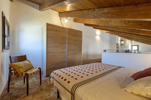 um quarto com uma cama grande e uma cadeira em La Casa di Valverde em Alghero