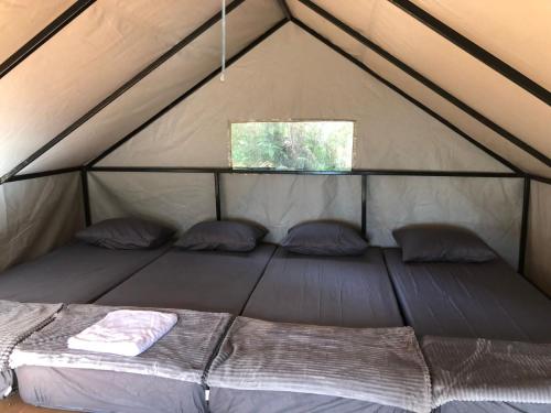 a bed in a tent with two pillows and a window at Kampung Rimba by Anrha in Bogor