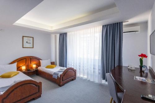 a hotel room with two beds and a desk and a window at Hotel Randy in Constanţa