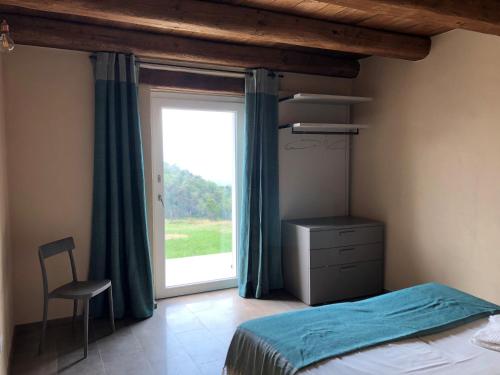 a bedroom with a bed and a window and a chair at Agriturismo Cascina Cornelli in Sassello
