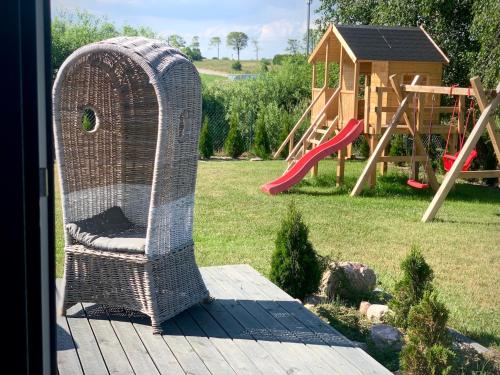 a wicker chair sitting on a deck with a playground at AHOY - Haus am Meer in Chłopy
