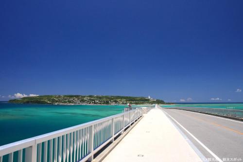 a bridge over the water with an island in the background at 【KouriGarden】古宇利島の海と緑と星を眺める一棟貸切別荘ヴィラ in Nakijin