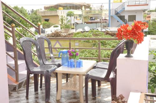 uma mesa e cadeiras numa varanda com flores em Classic Homestay em Hospet