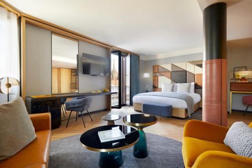 Kimpton Vividora Hotel by IHG في برشلونة: غرفة فندق بها سرير وأريكة