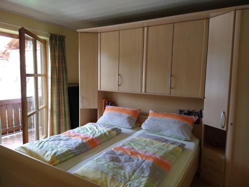 a bedroom with two beds and cabinets and a window at Ferienwohnung Achental in Marquartstein