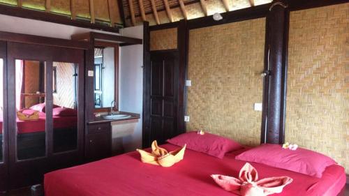 una camera con 2 letti con lenzuola rosse e uno specchio di Villa Manouria - Marcel a Padangbai