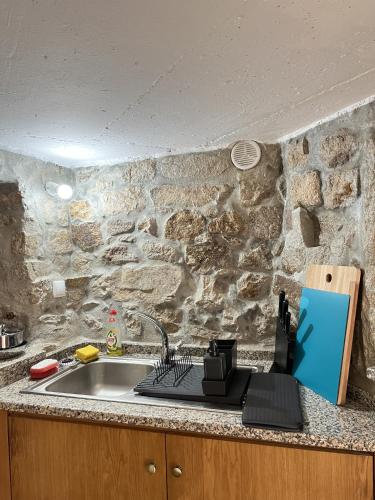 a kitchen counter with a sink and a stone wall at CASA DE CAMPO BENFEITO in Campo Benfeito