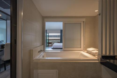 a bathroom with a tub, sink and mirror at Andamantra Resort and Villa Phuket - SHA Extra Plus in Patong Beach