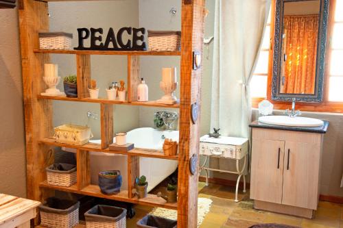 Four Seasons Guesthouses في Lephalale: حمام مع رف خشبي مع حوض وحوض استحمام